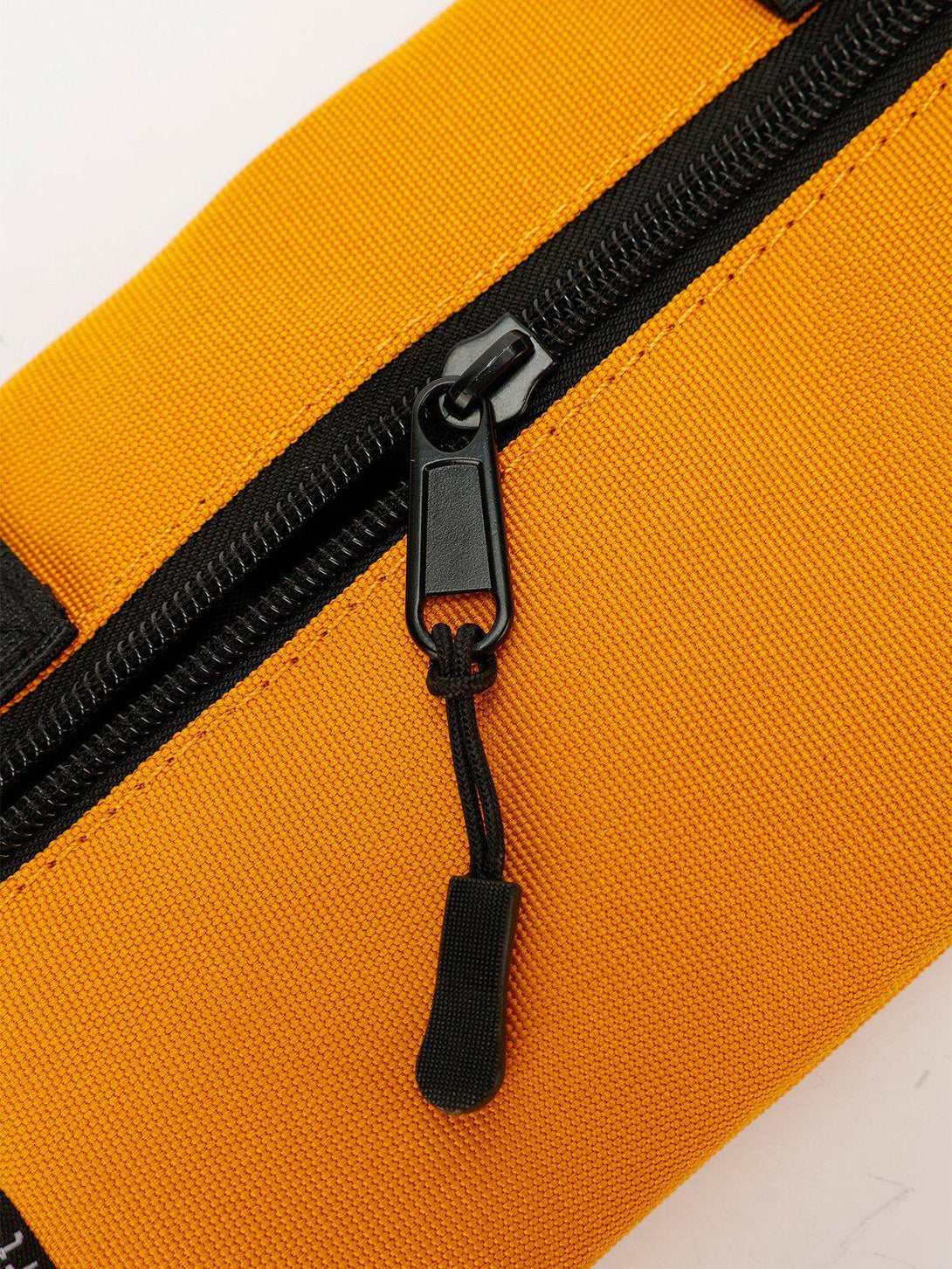A close-up of TALISHKO's yellow crossbody bag, highlighting the sturdy black zipper detail.