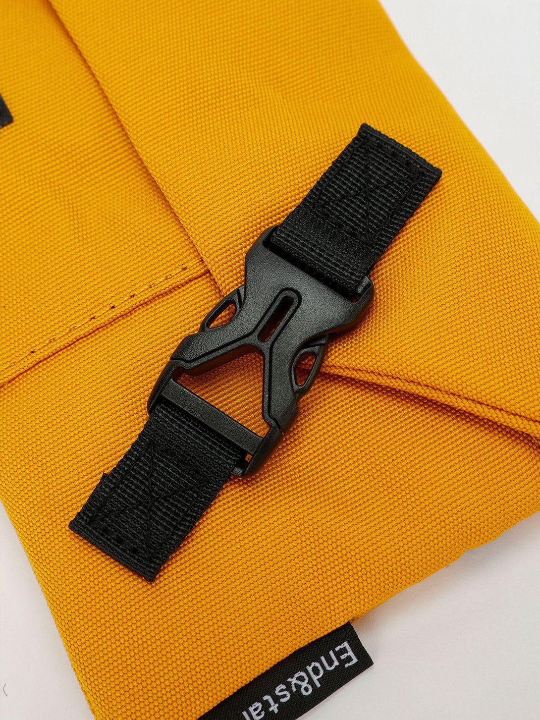 A detailed view of TALISHKO's yellow crossbody bag, showcasing the black buckle and strap.