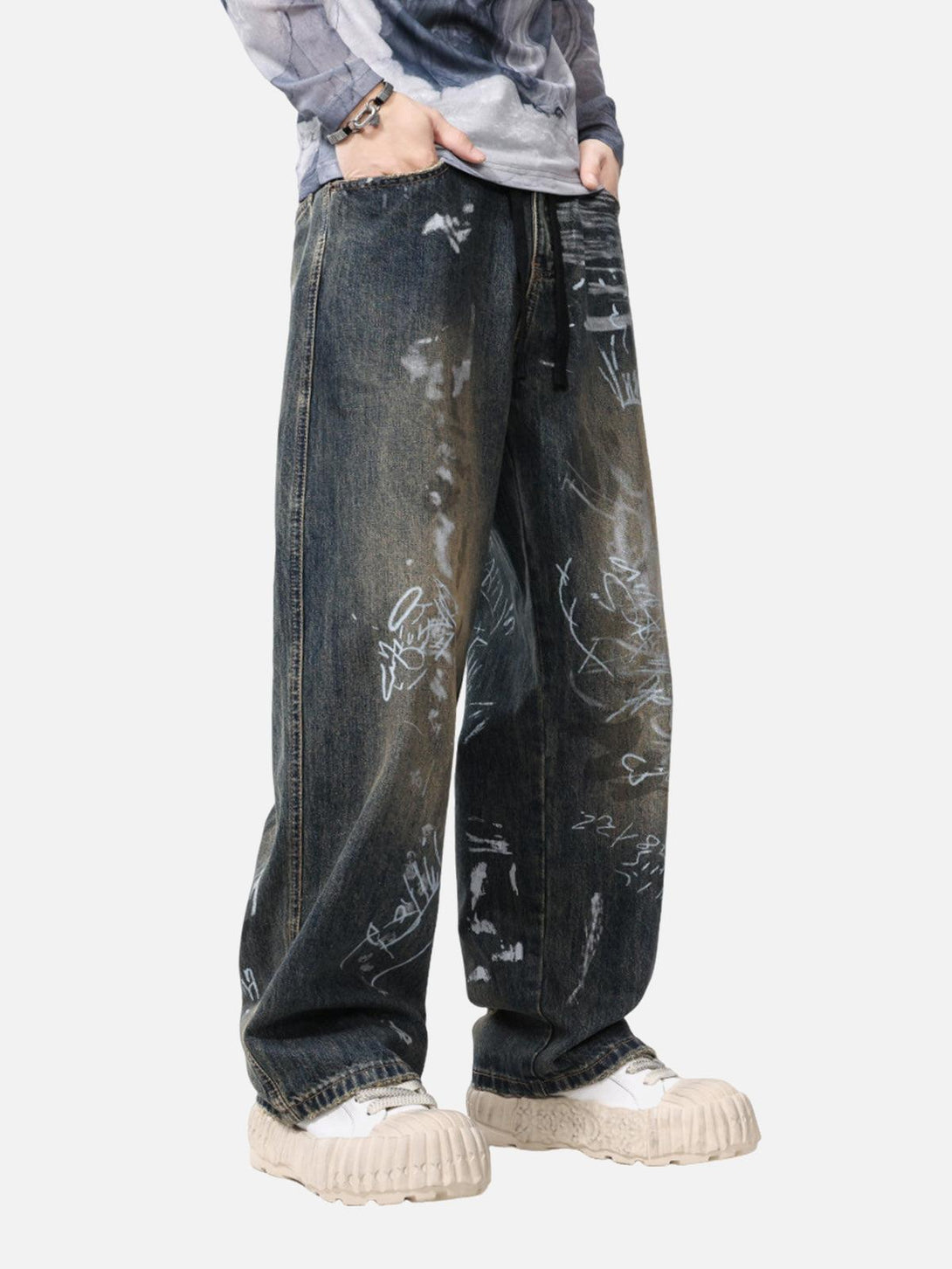 Model wearing TALISHKO baggy jeans with hand-painted graffiti, paired with chunky sneakers.