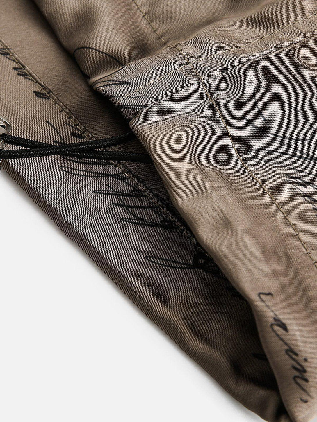 Detailed fabric and stitching of TALISHKO silk shorts, showcasing elegant script pattern.