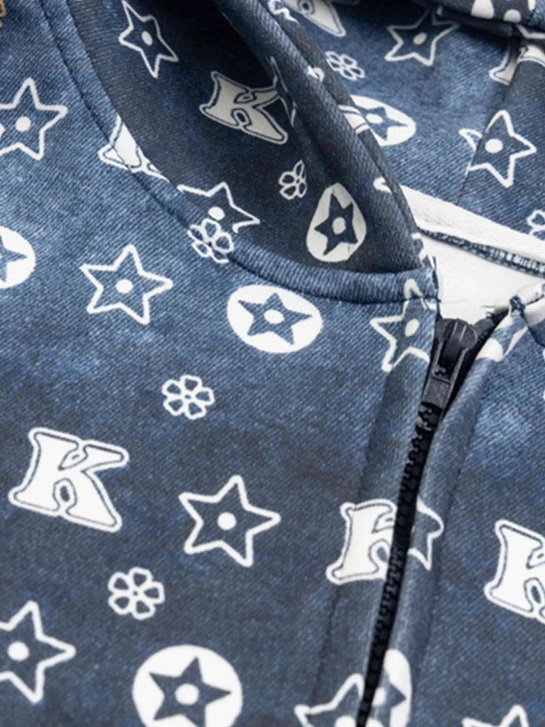 Detailed look at TALISHKO zip-up hoodie with star and letter pattern on a blue fabric.