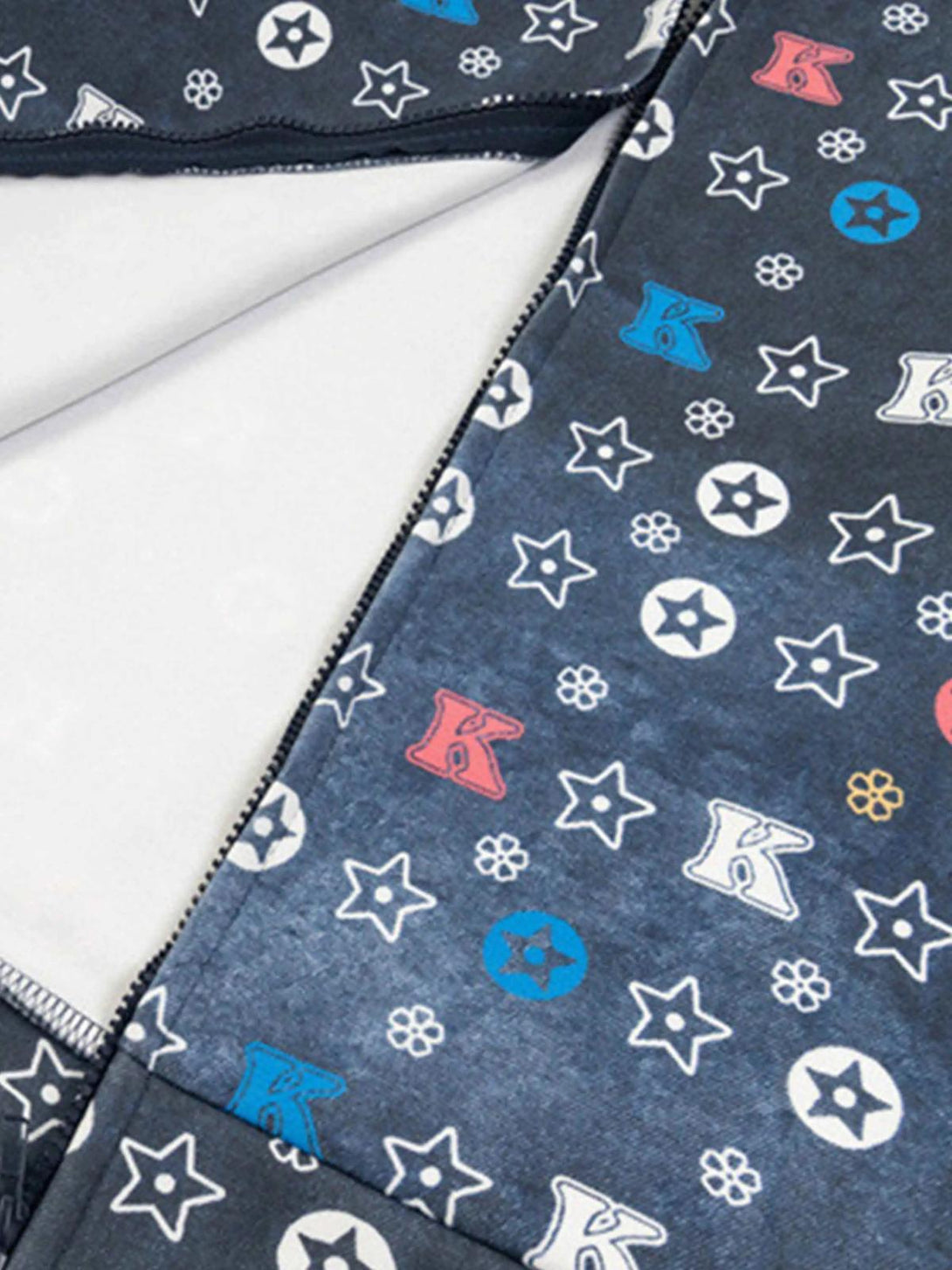 Focusing on the pattern details of TALISHKO hoodie, featuring stars and letters on dark fabric.