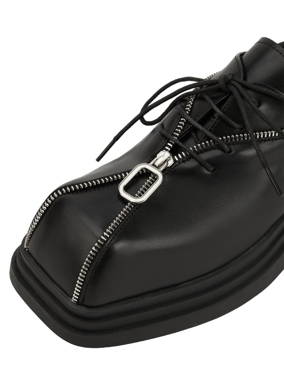 A tight crop highlighting TALISHKO's black leather shoes with a distinctive zipper design.