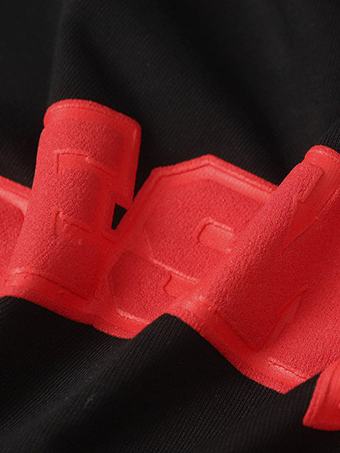 A close-up of the textured red graphic detail on TALISHKO's black T-shirt.