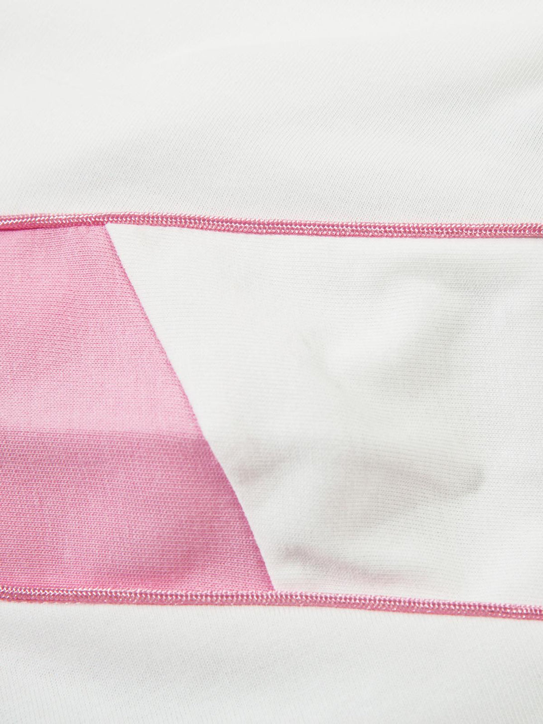 A tight crop highlighting the pink and white fabric detail of a TALISHKO oversized long sleeve T-shirt.