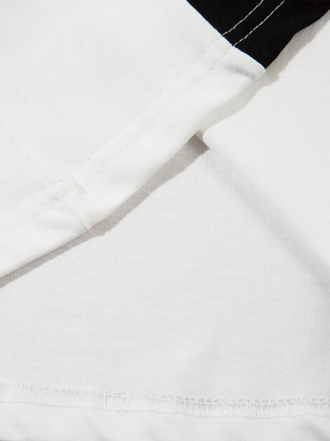 Detailed fabric and stitching of a TALISHKO oversized long sleeve T-shirt in white and black.