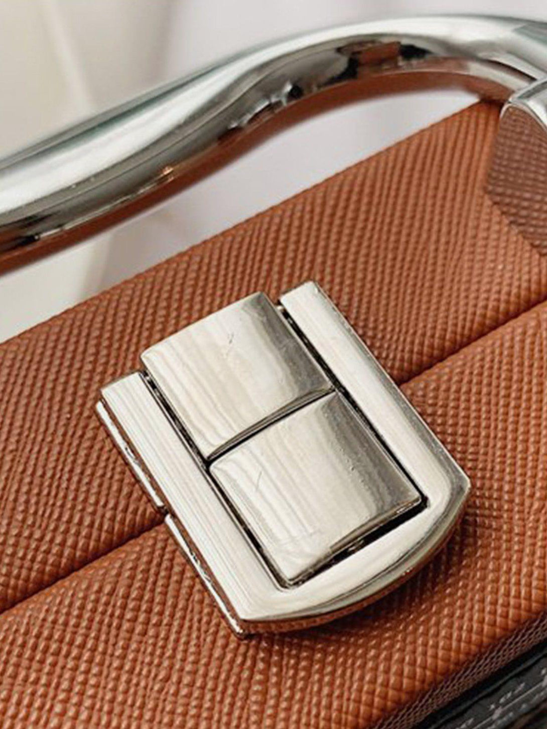 Intricate look at the metallic clasp detail on a TALISHKO crossbody bag, highlighting its unique design.