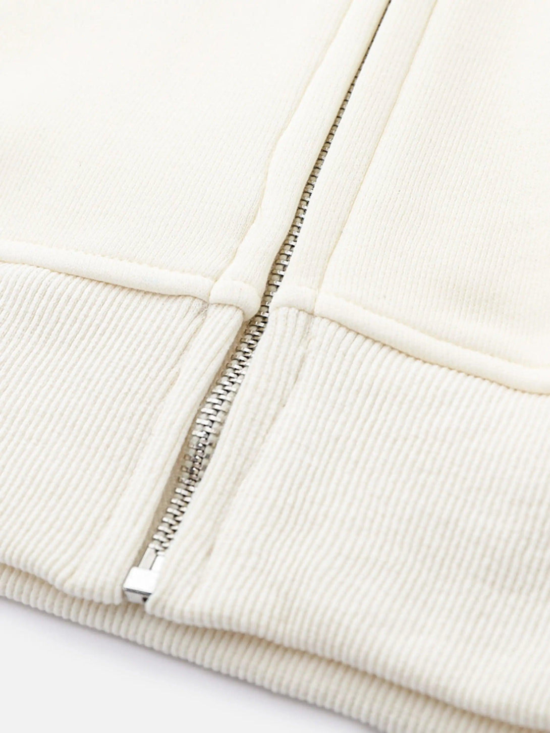 A detailed view of the TALISHKO hoodie zipper, highlighting the cream ribbed texture.