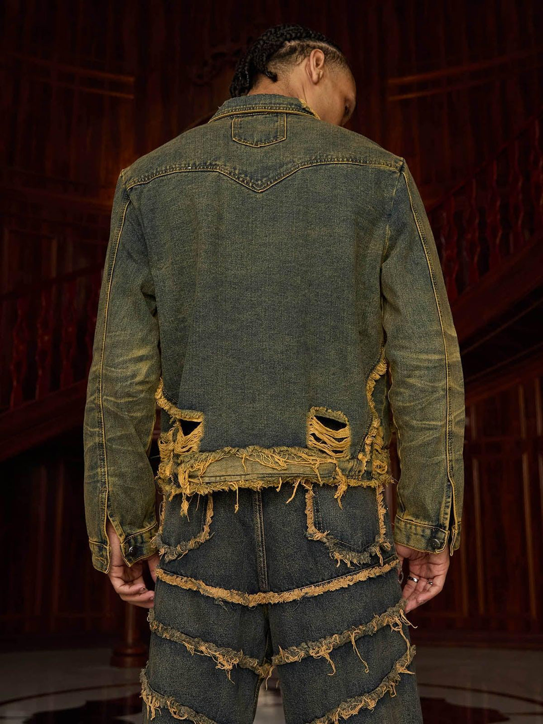 Back view of TALISHKO's distressed denim jacket with raw edges, paired with matching pants.