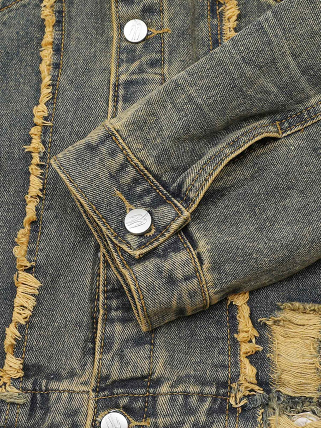 Detailed fabric and stitching of TALISHKO's raw edge distressed denim jacket sleeve.