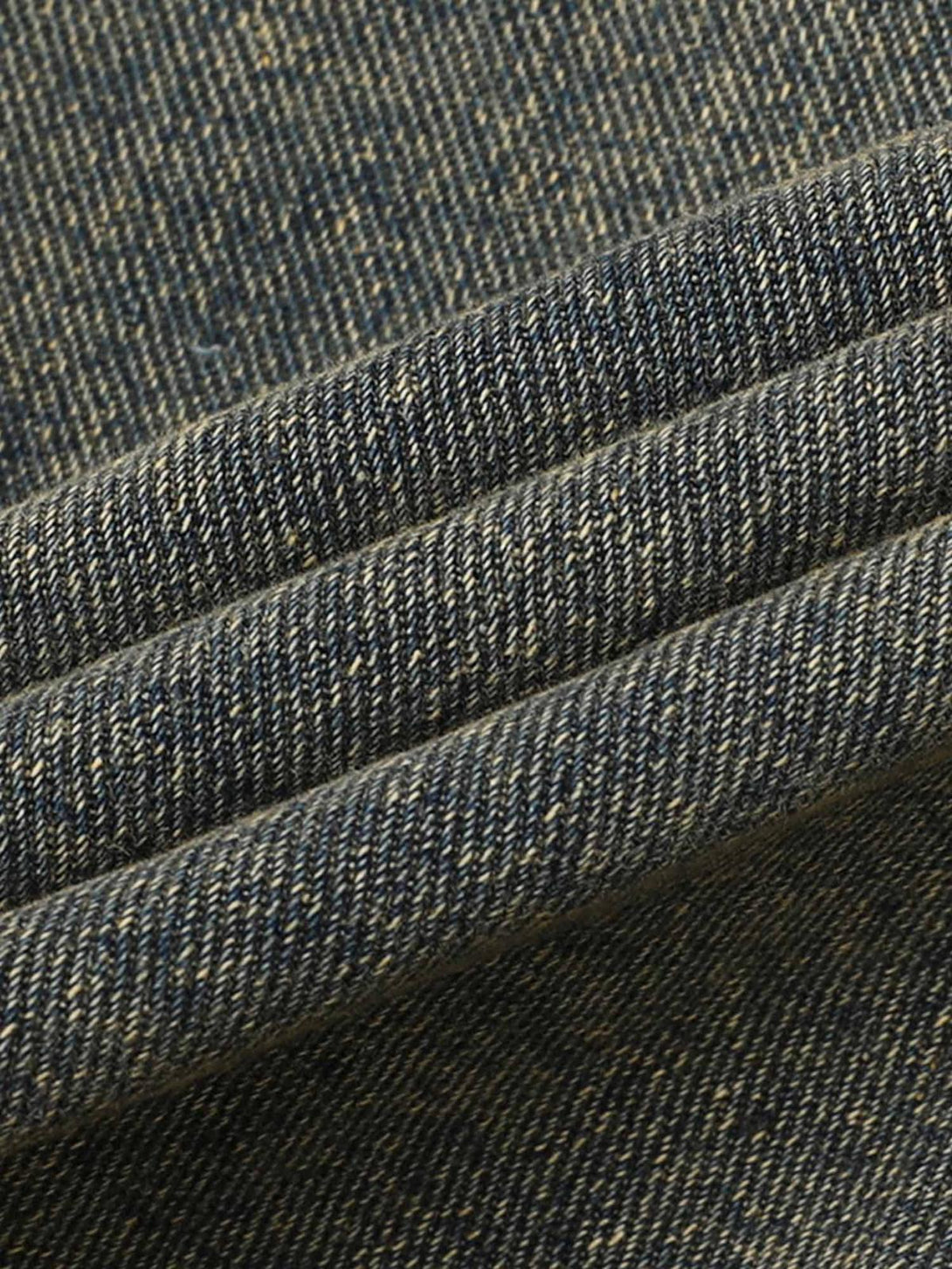 Zoomed-in texture of TALISHKO's raw edge distressed denim fabric, showcasing intricate detail.