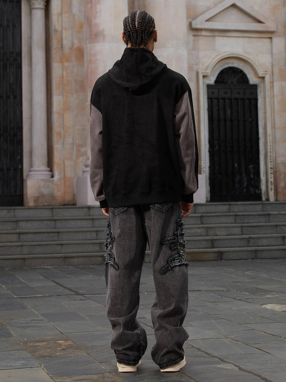 Back view of TALISHKO raw edge patch straight jeans paired with a hoodie, embracing streetwear vibes.