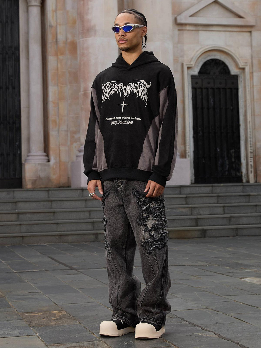Model in TALISHKO raw edge patch jeans and hoodie, embodying a bold streetwear look.