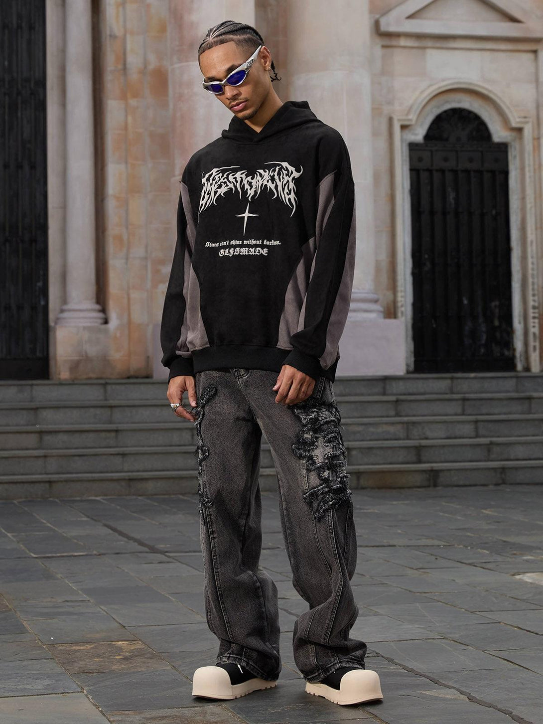 Model wearing TALISHKO raw edge patch jeans with a hoodie, highlighting edgy street fashion.