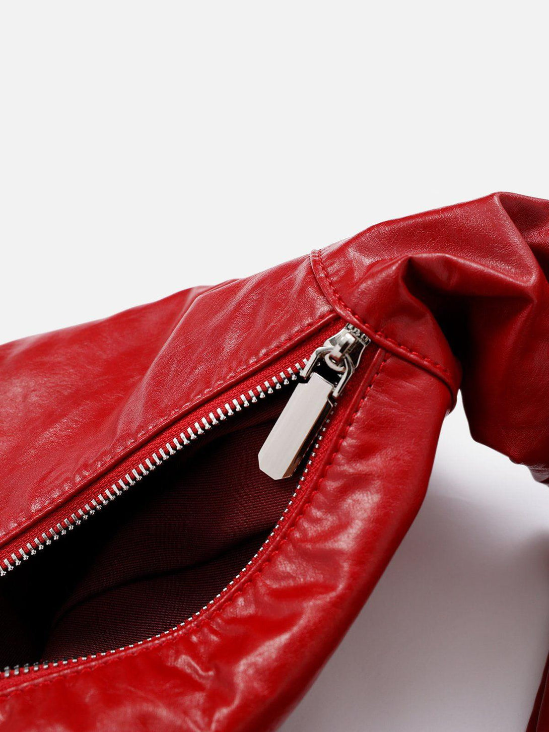 A close-up of TALISHKO's red faux leather bag, highlighting the zipper and glossy texture.