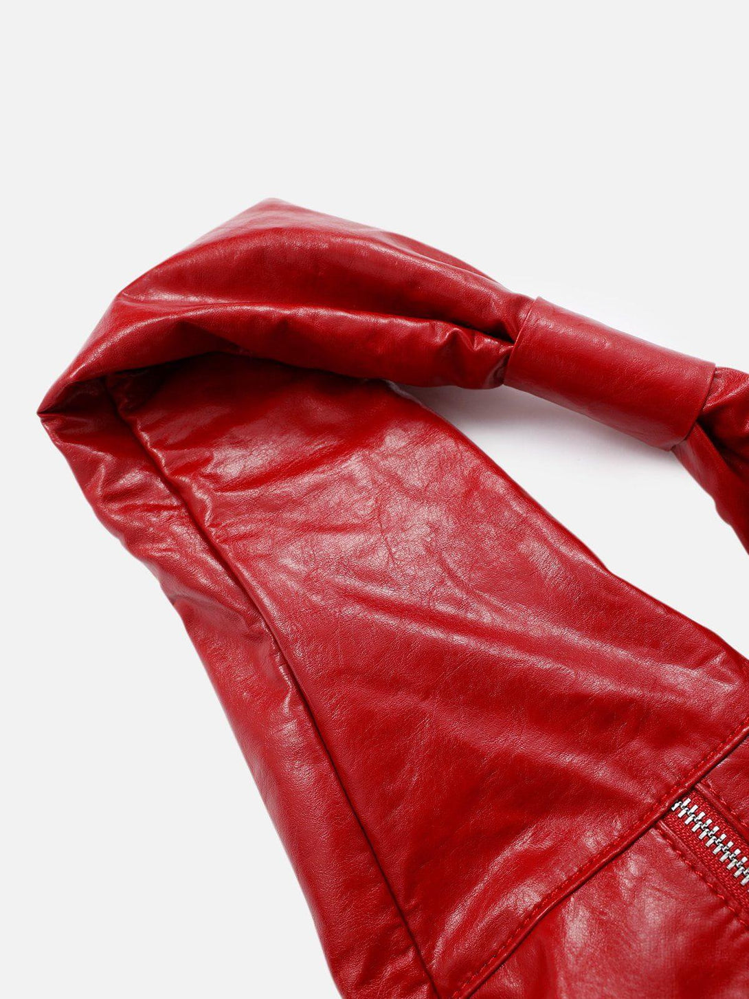 A tight crop highlighting TALISHKO's red faux leather bag's glossy texture and rich color.
