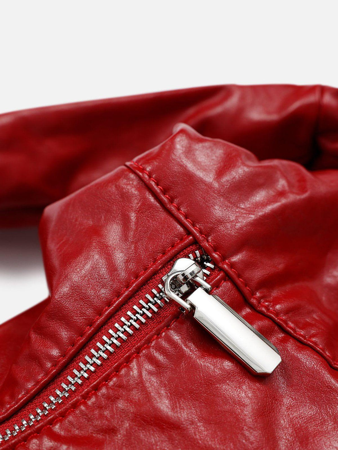 A detailed look at the TALISHKO red faux leather bag's zipper and texture.