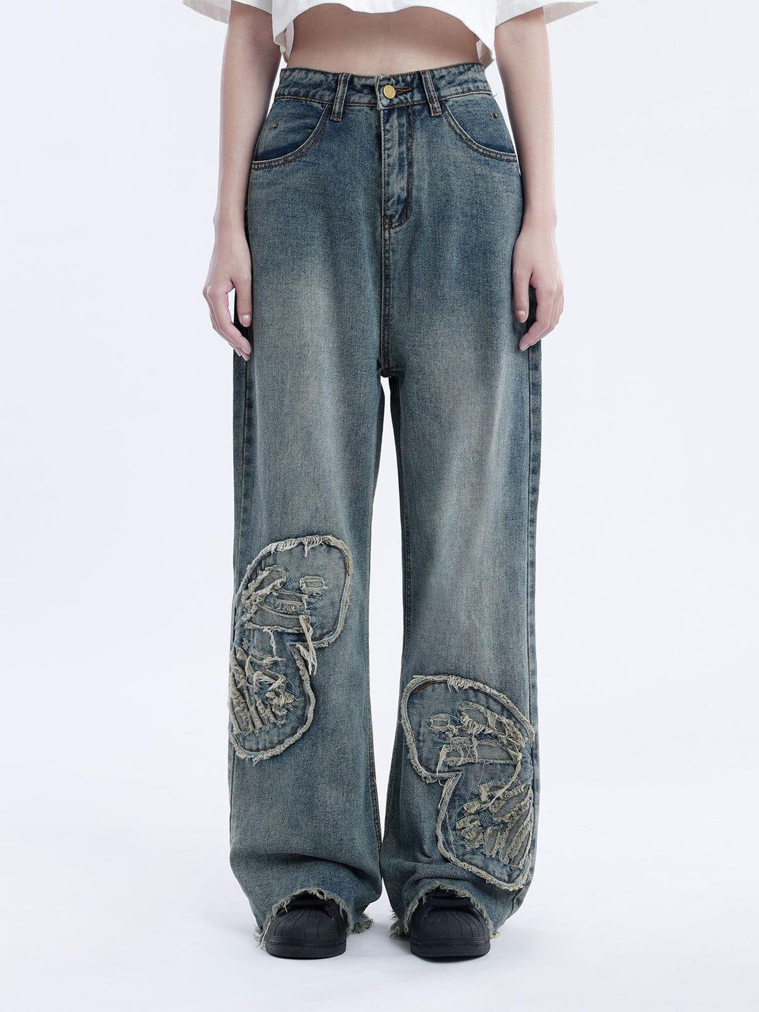 Model wearing TALISHKO loose jeans with frayed butterfly patches and a relaxed fit.
