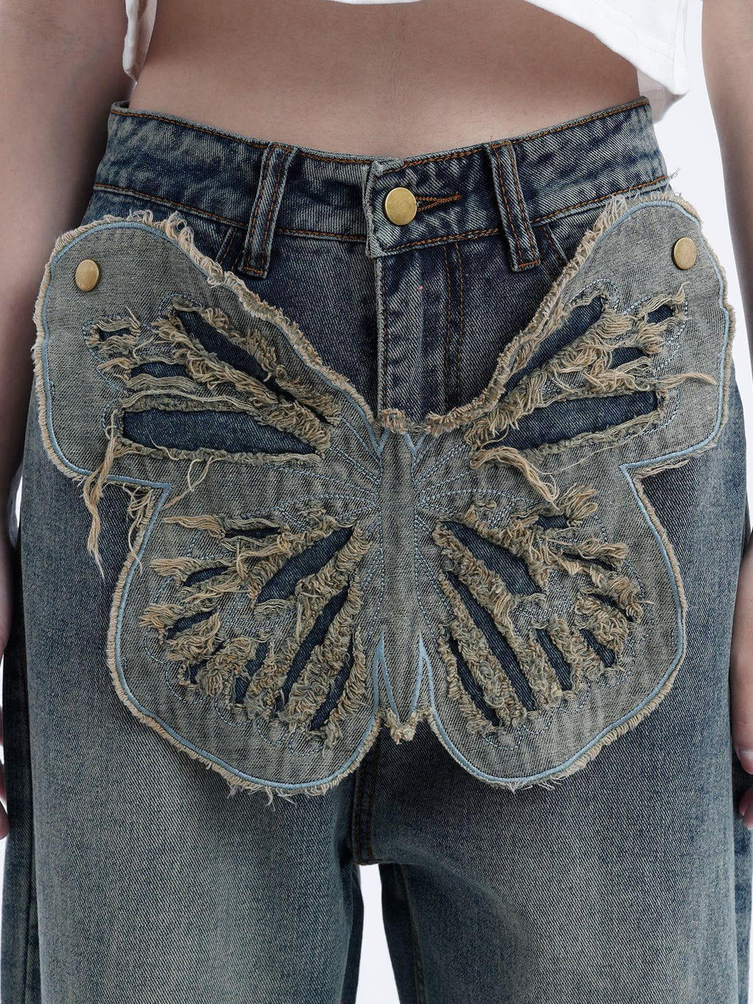 TALISHKO jeans with a large, frayed butterfly design, emphasizing unique denim texture.