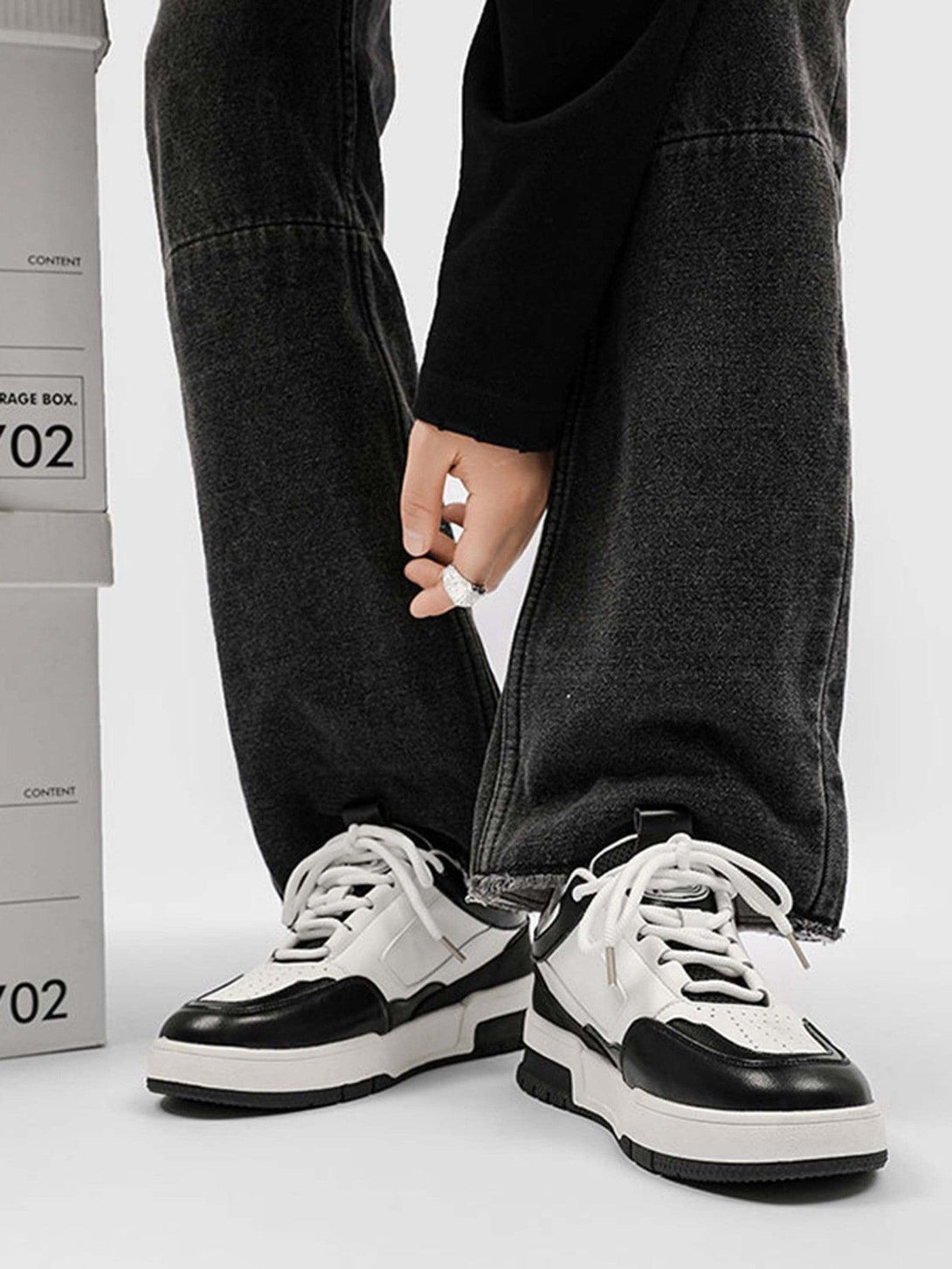 A close-up of TALISHKO retro slip-on sneakers in black and white, styled with dark denim.