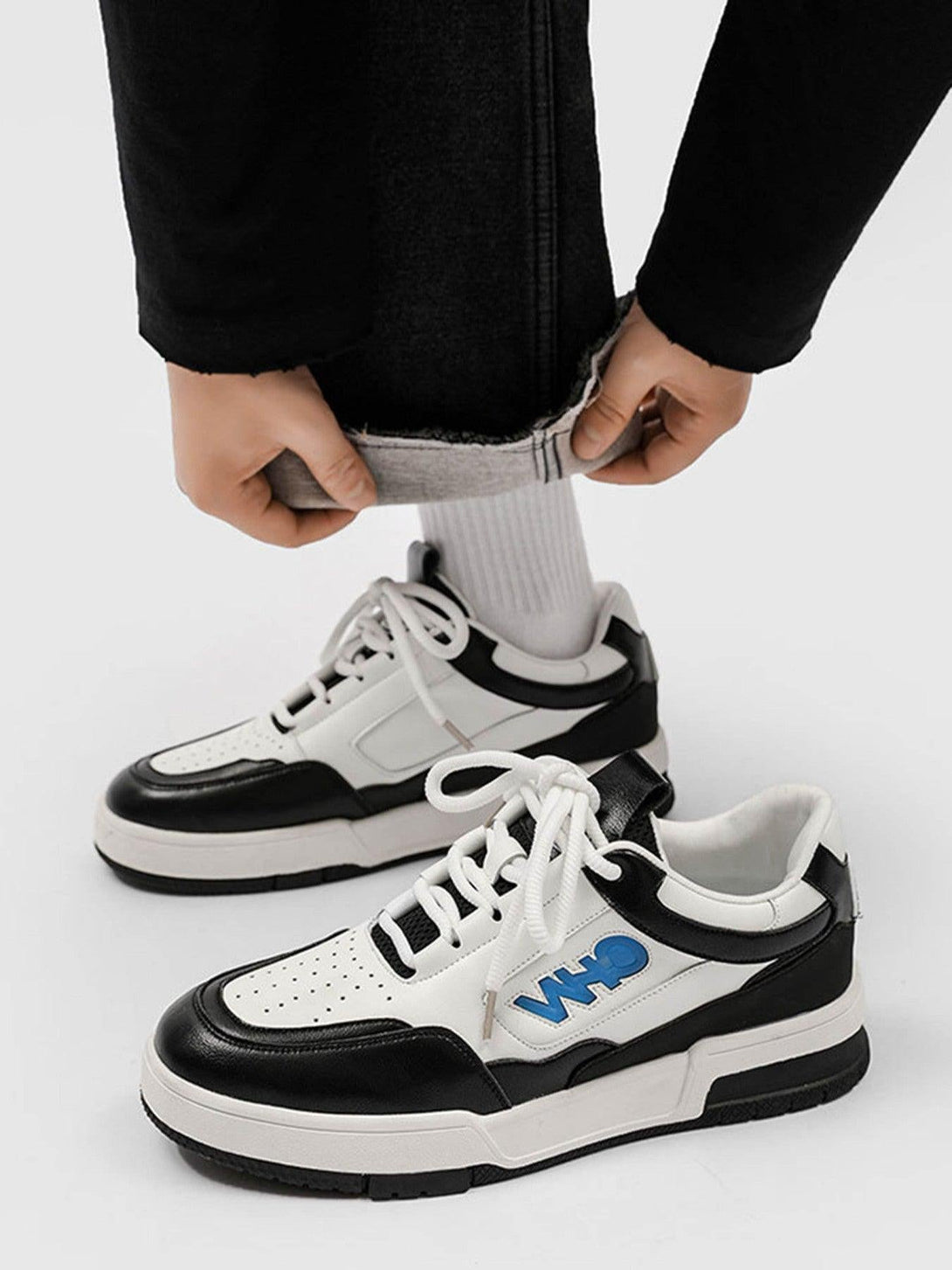 TALISHKO retro sneakers in black and white, styled with rolled-up pants for a casual look.