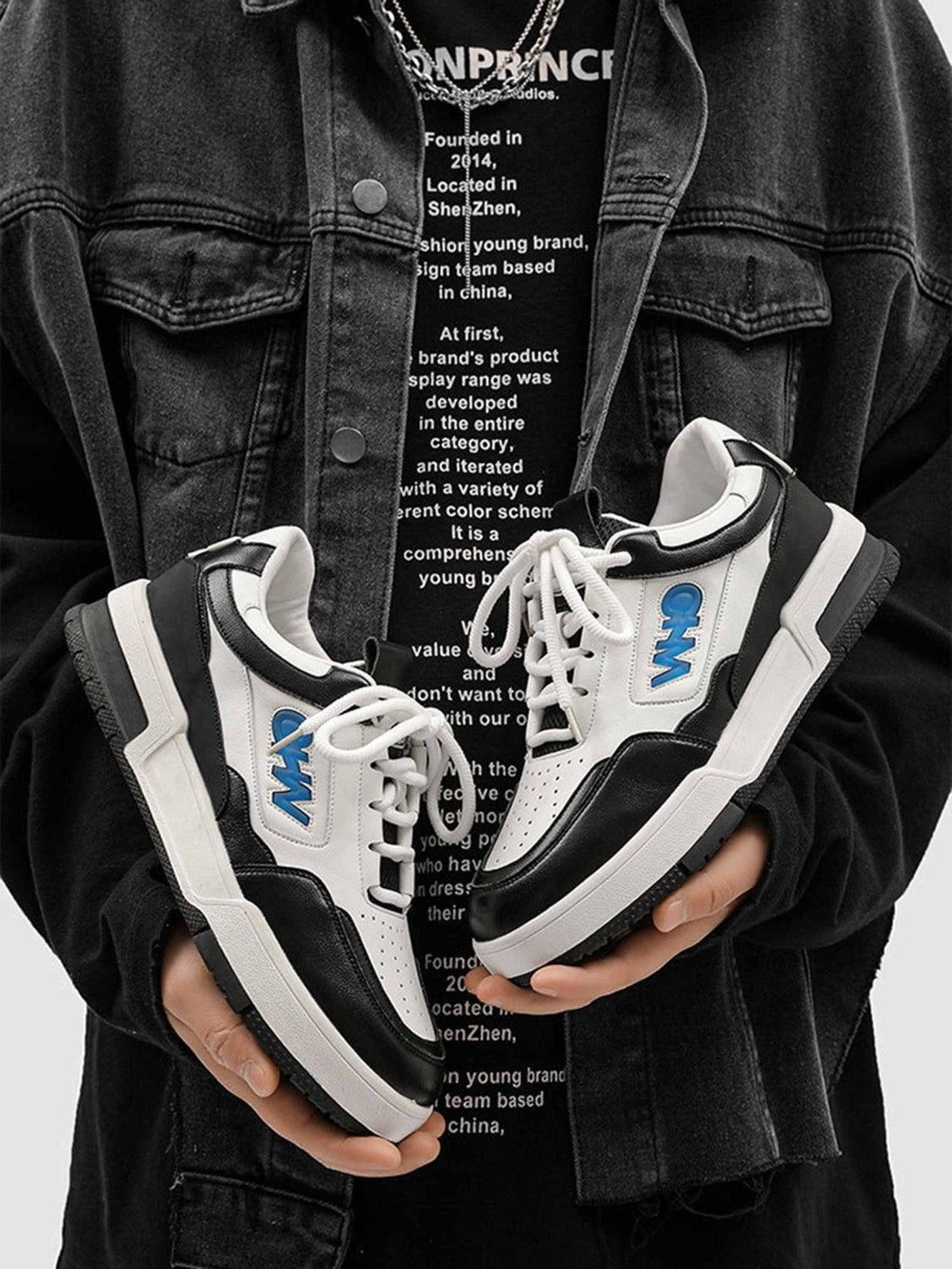 TALISHKO retro sneakers in black and white held in hands, showcasing bold urban style.