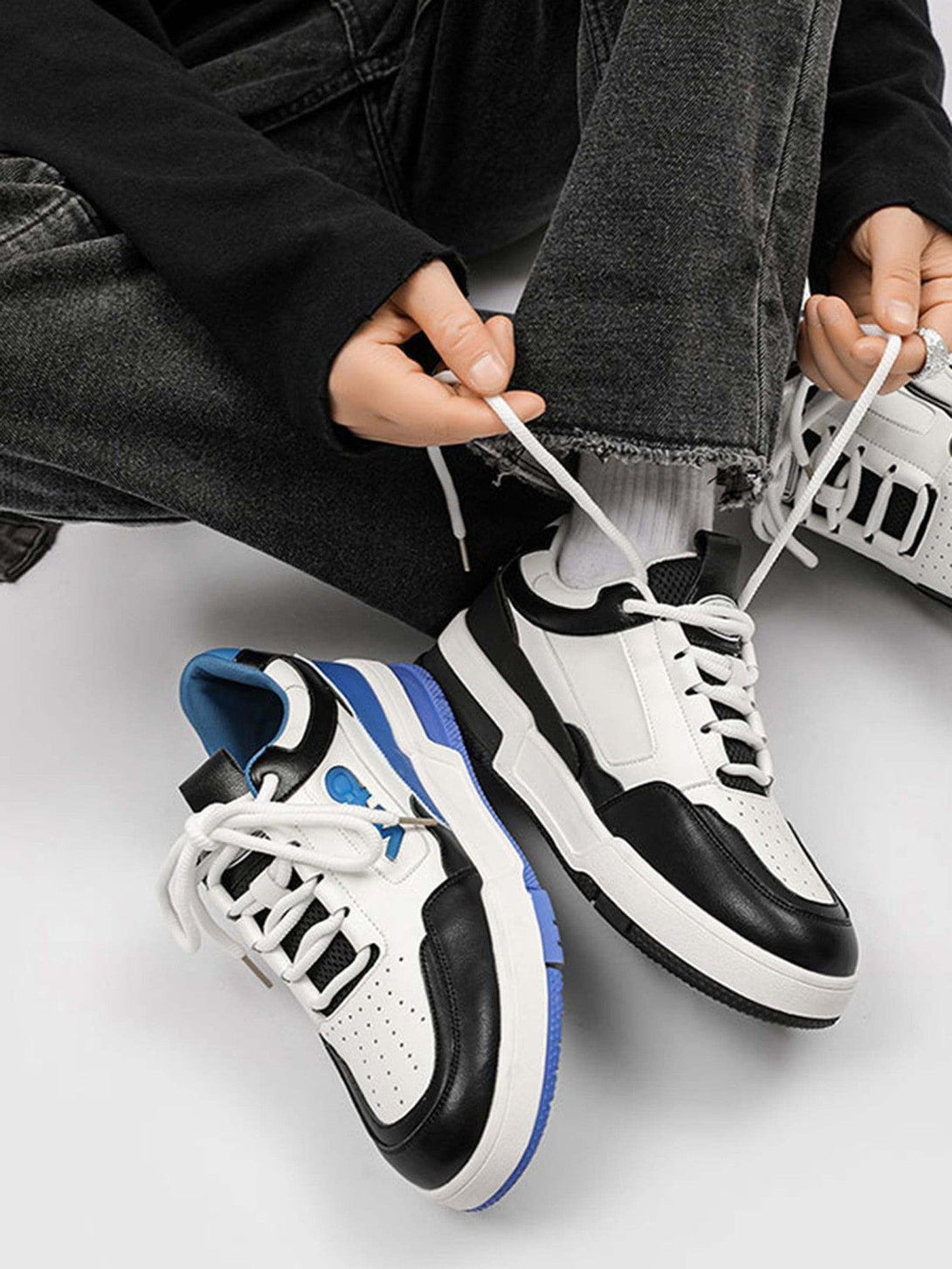 TALISHKO sneakers in black and white, styled with dark denim for a trendy street vibe.