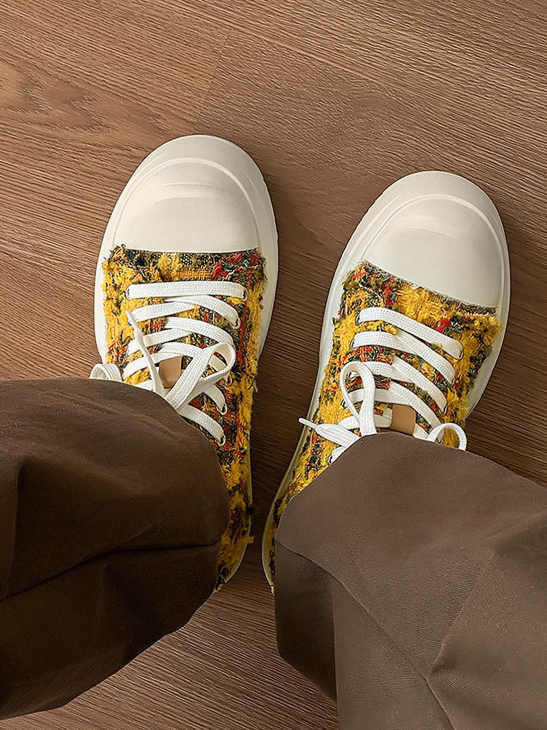 Retro canvas sneakers by TALISHKO in multicolored texture, paired with brown pants on a wooden floor.