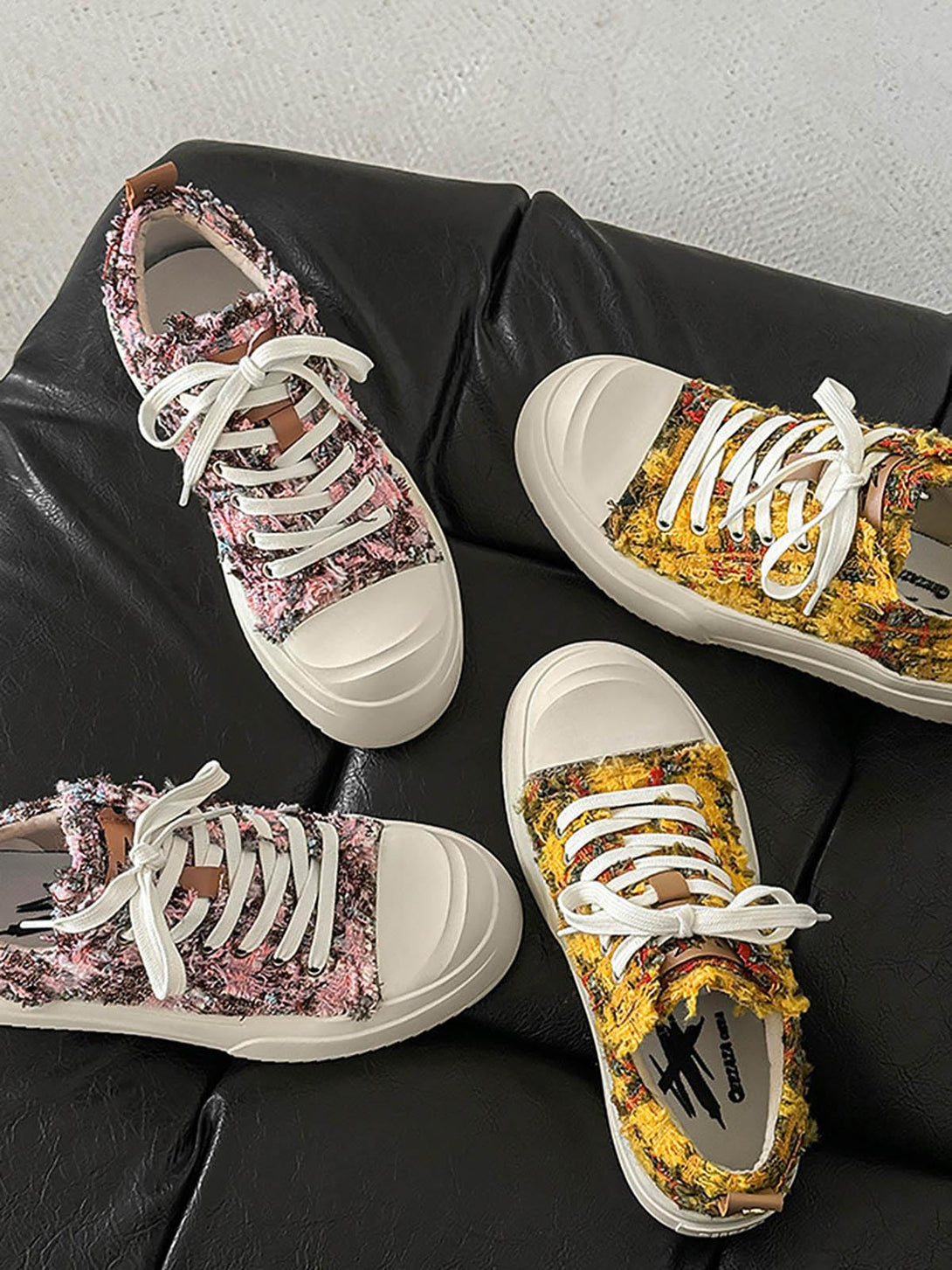 TALISHKO sneakers in pink and yellow textures, set on a black leather couch for a stylish look.