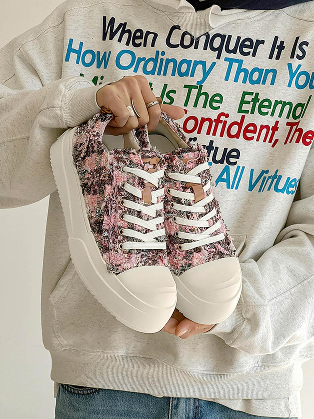 TALISHKO sneakers in a vibrant pink texture, held against a graphic hoodie for a casual vibe.