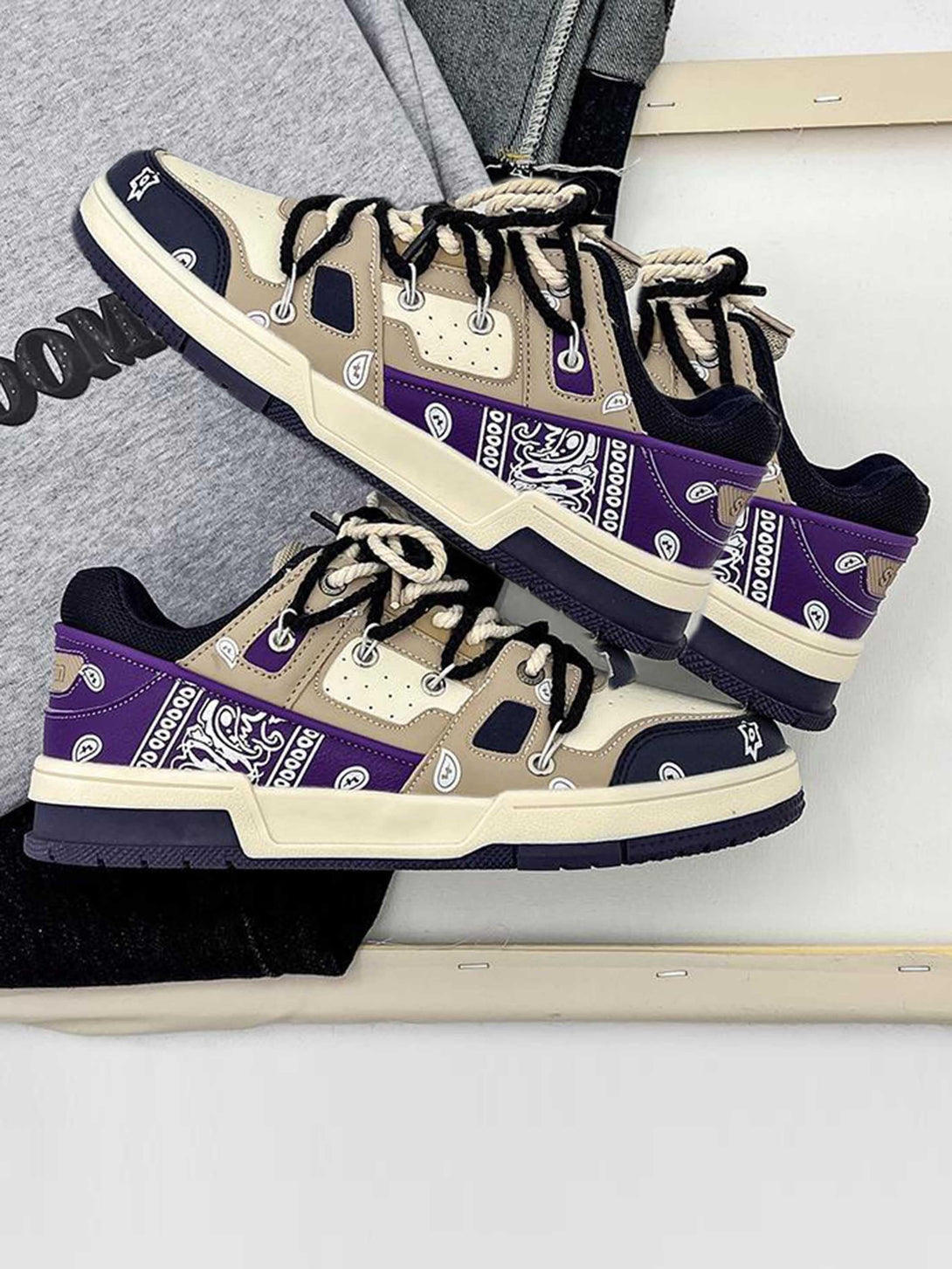 TALISHKO sneakers featuring a beige and purple paisley design, stylishly laid on casual attire.