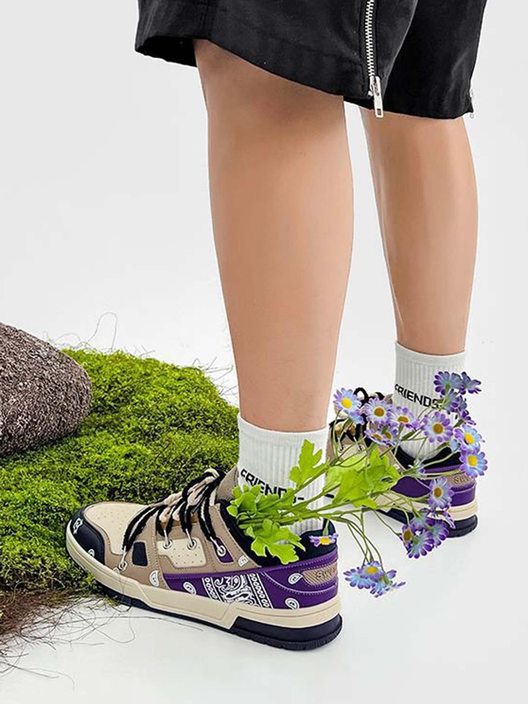 TALISHKO sneakers in beige and purple with floral detail, styled with "FRIENDS" socks on grass.