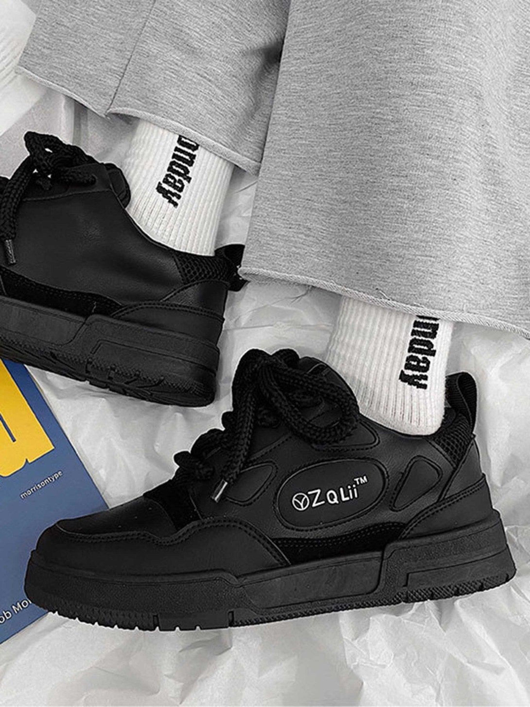 Black TALISHKO retro board shoes styled with gray pants and white branded socks on a soft surface.