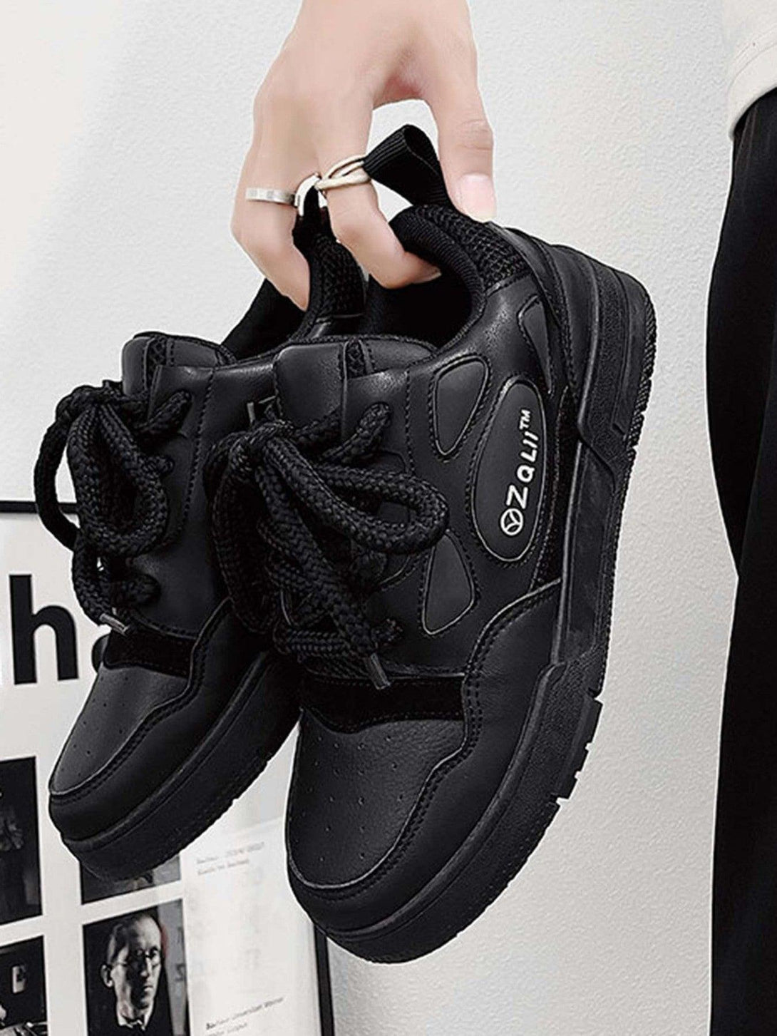 TALISHKO retro casual board shoes in black, highlighted in a stylish hand-held close-up.