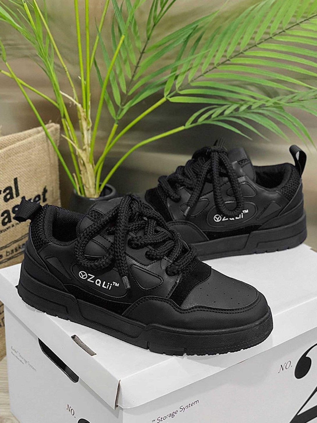 Black retro casual board shoes by TALISHKO displayed on a box with lush greenery.