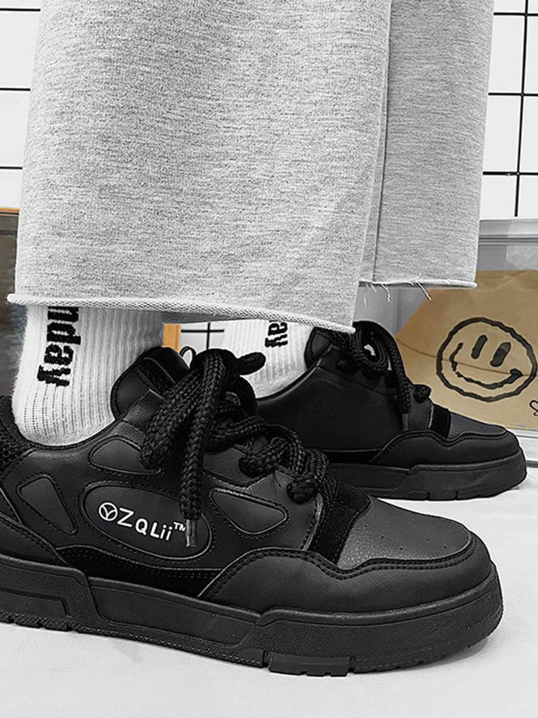 TALISHKO retro casual board shoes in black, styled with gray pants and branded socks for a chic look.