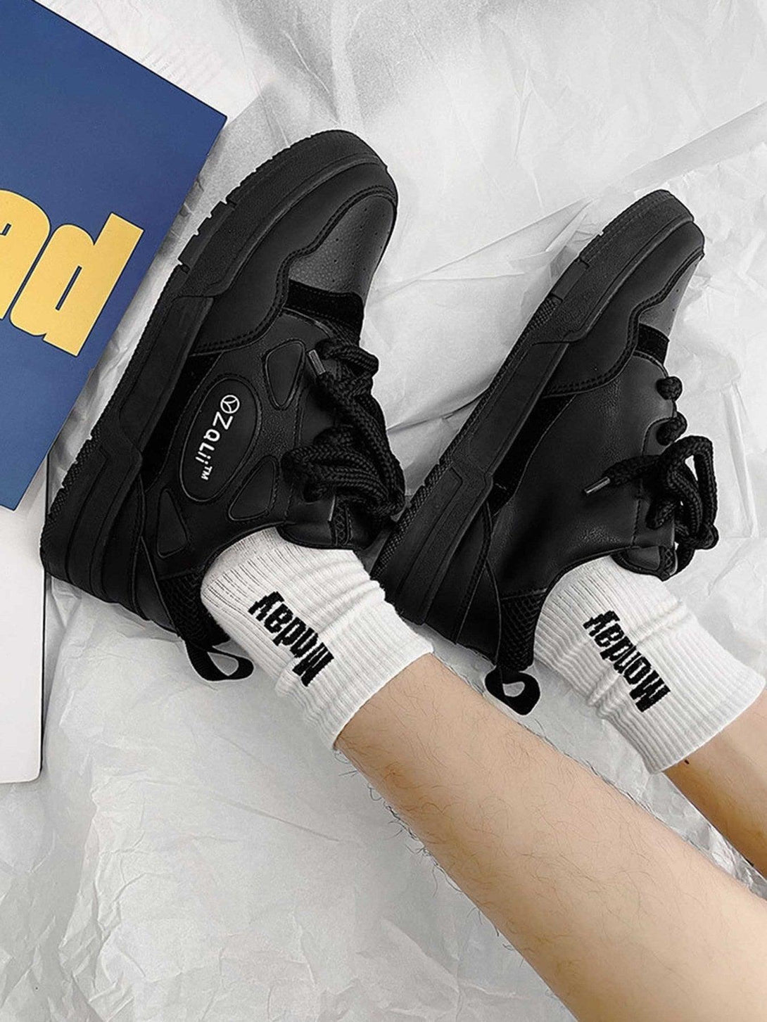 Black retro casual board shoes by TALISHKO paired with white branded socks on a soft surface.