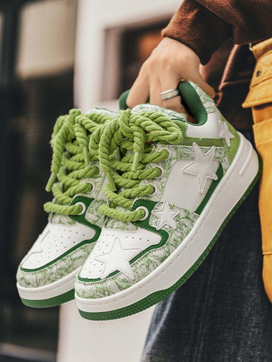 TALISHKO retro casual sneakers with green star accents, held by a person in casual attire.