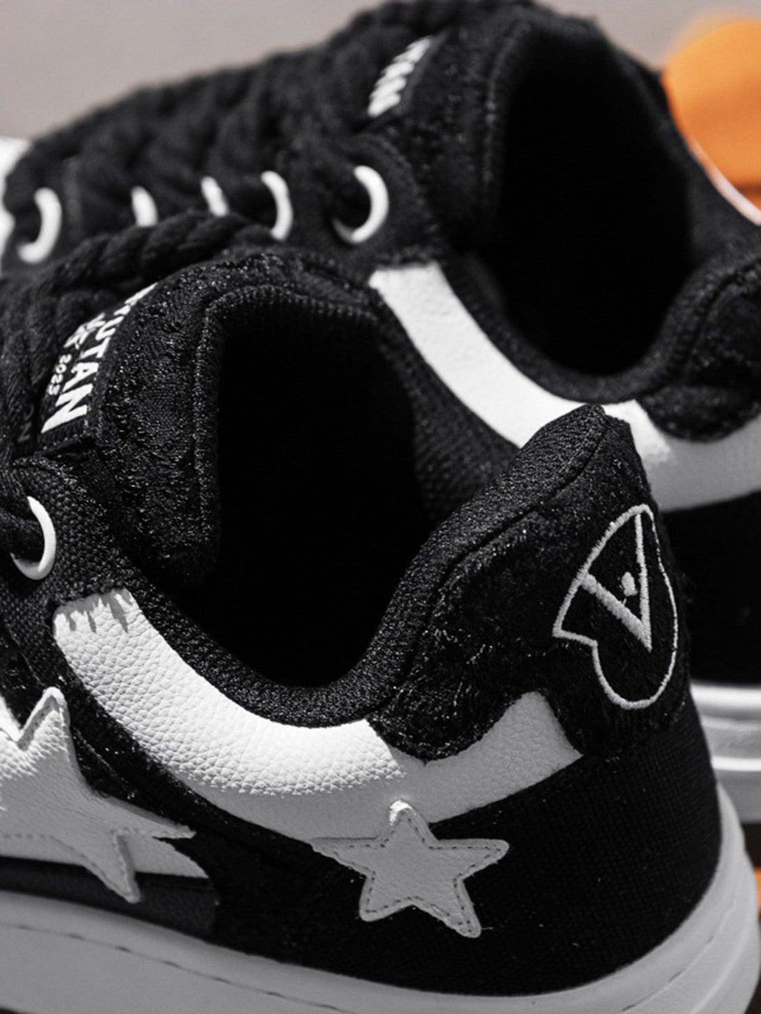 Close-up of TALISHKO black retro sneakers with star accents and textured details.
