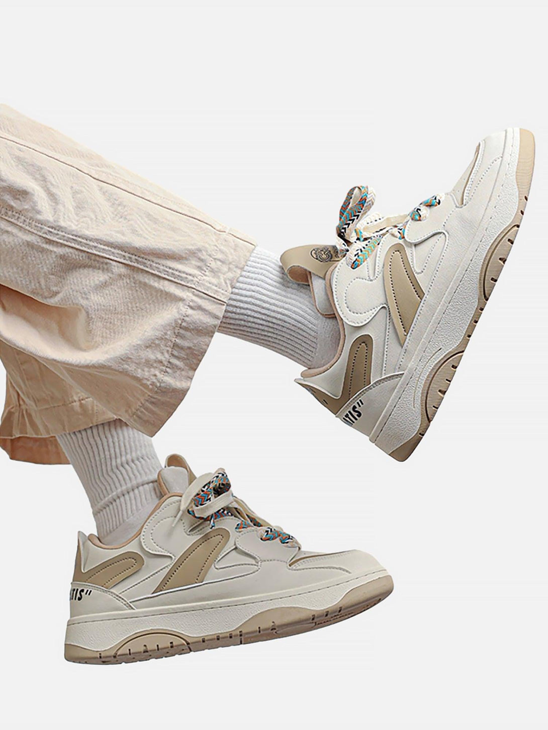 TALISHKO retro sneakers in beige, worn with casual pants, highlighting colorful laces and style.