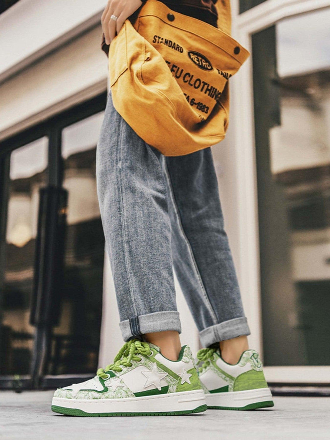 TALISHKO retro casual sneakers with green star accents, styled with rolled jeans and a yellow bag.