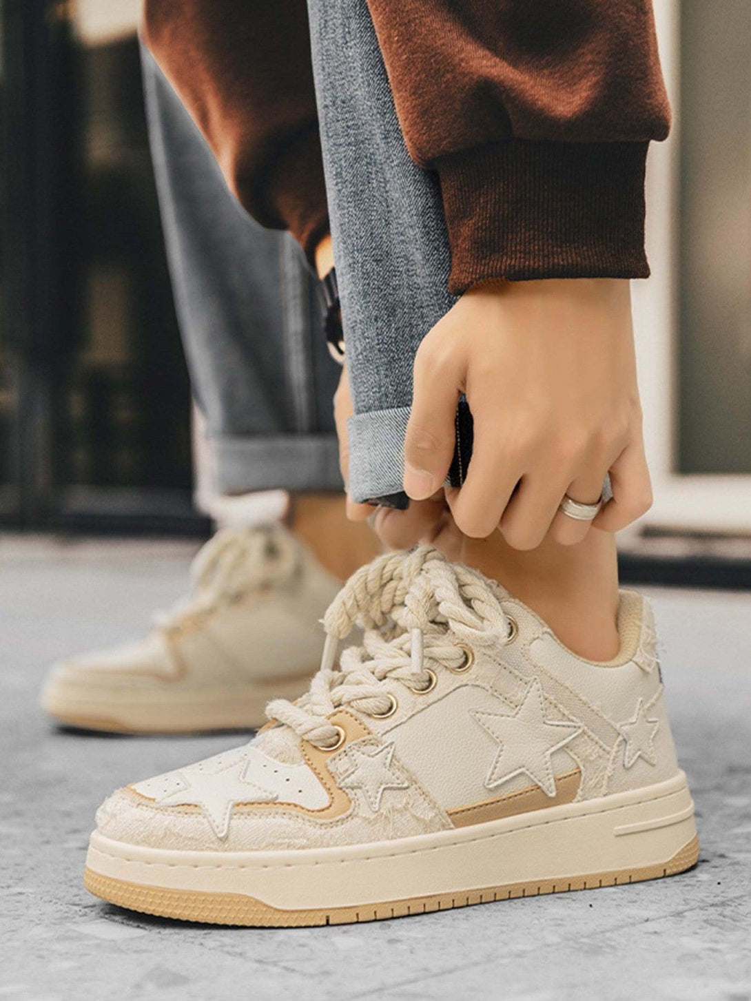 A close-up of TALISHKO retro casual sneakers with star details, styled with rolled jeans.