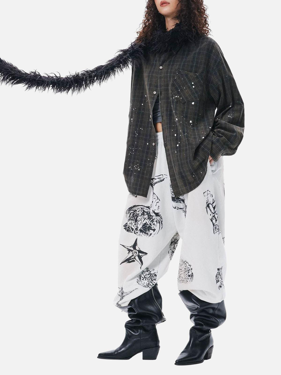 Model in TALISHKO retro plaid shirt with graphic pants and boots, exuding eclectic style.