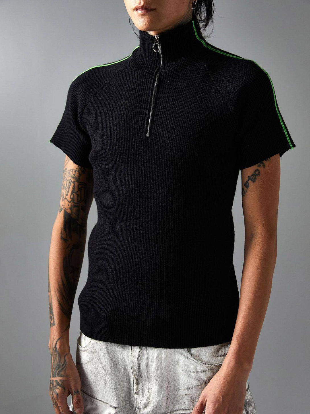 Model sporting a retro black quarter zip-up T-shirt by TALISHKO, styled with light jeans.