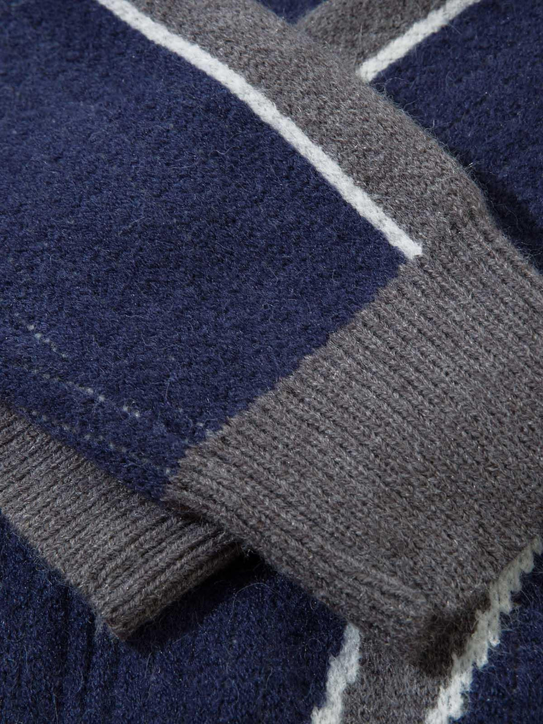 A tight crop highlighting the soft texture and contrast knit pattern of a TALISHKO cardigan.