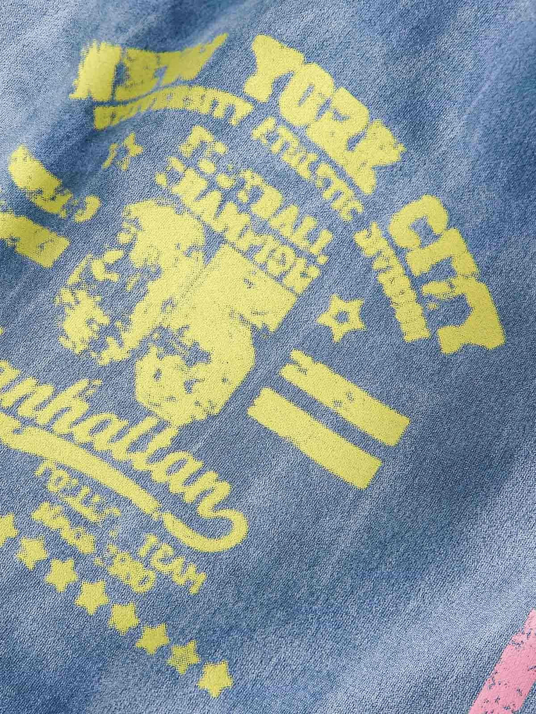 Yellow graphic detail on a blue suede track jacket by TALISHKO, enhancing retro style.