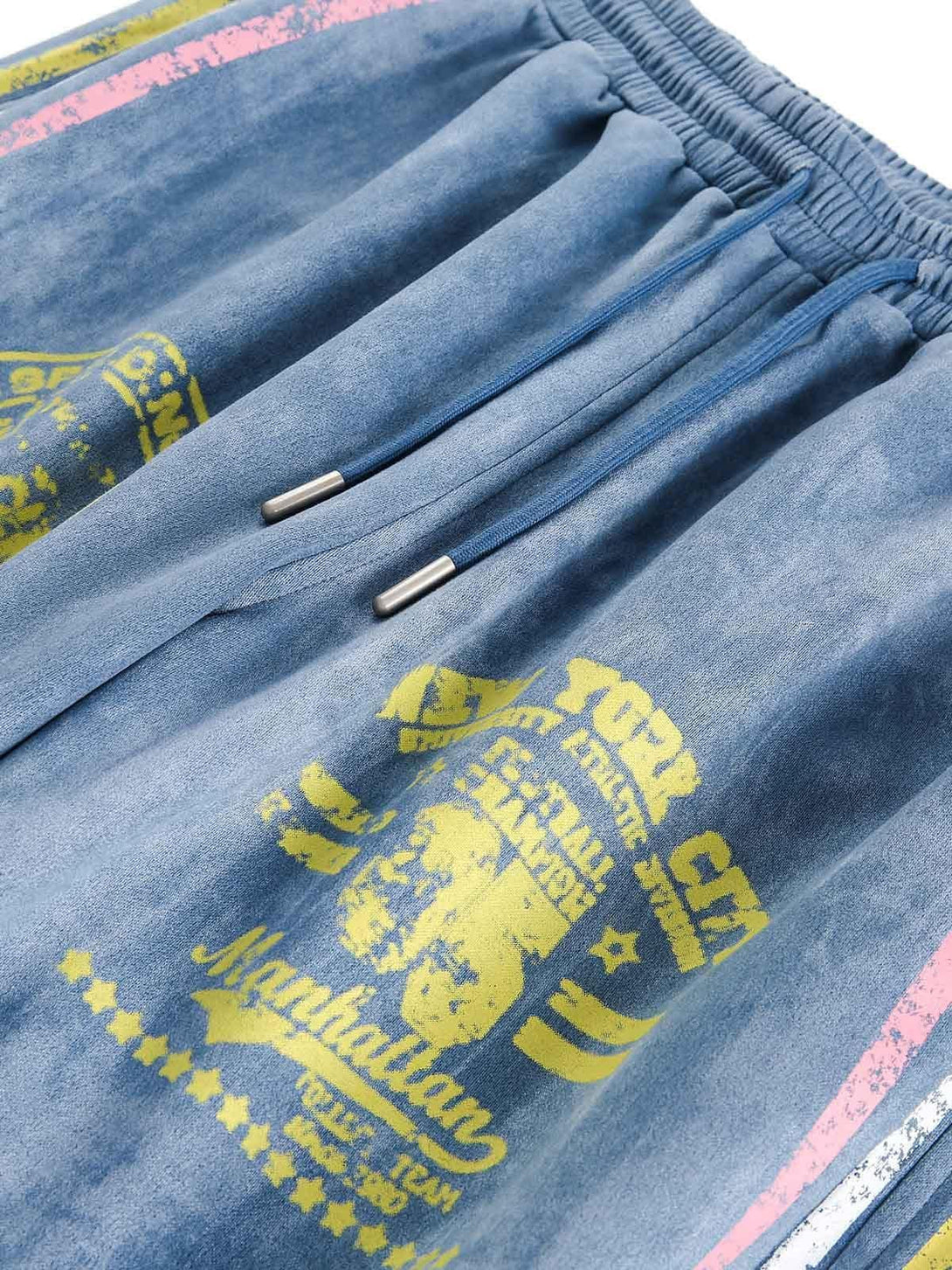 Texture and pattern showcased on TALISHKO track pants with vintage yellow graphics on blue suede.