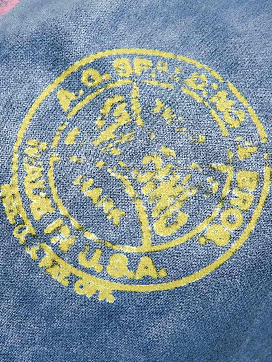 A close-up of TALISHKO track pants featuring vibrant yellow graphics on soft blue fabric.