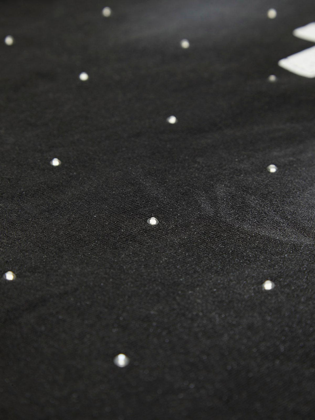 A tight crop highlighting TALISHKO's black T-shirt with shimmering crystal dot details.