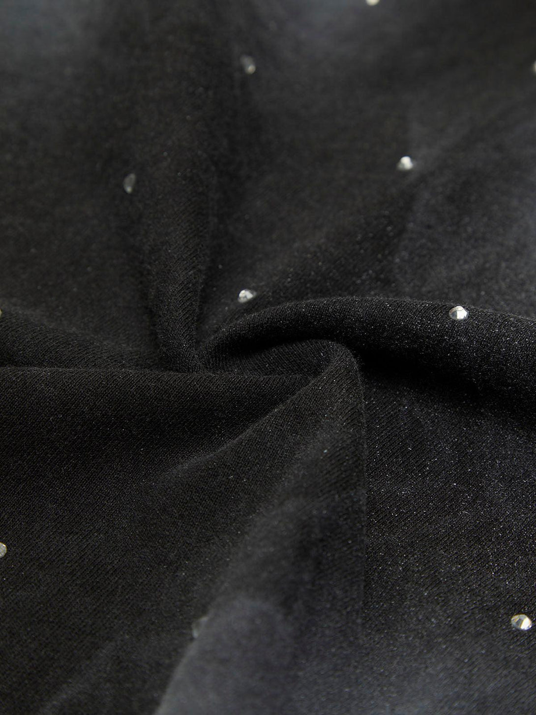 A detailed view of TALISHKO's black T-shirt fabric with scattered crystal embellishments.